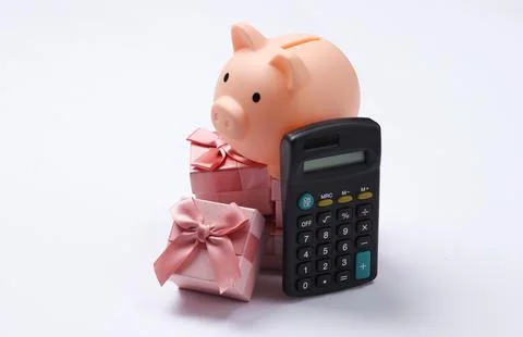 Piggy bank on stack of gift boxes and calculator. White background 스톡 사진