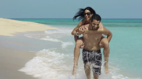 Piggyback ride with happy man and woman on the beach Stock Footage