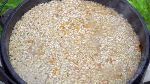 Pilaf in a cauldron over a fire. Rice and carrot Stock Footage 69206381