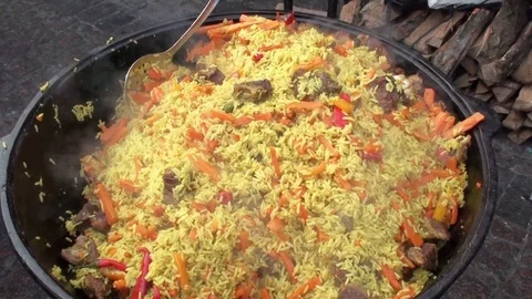 Pilaf is cooked on the grill in a large cauldron. Stock Footage 75802437