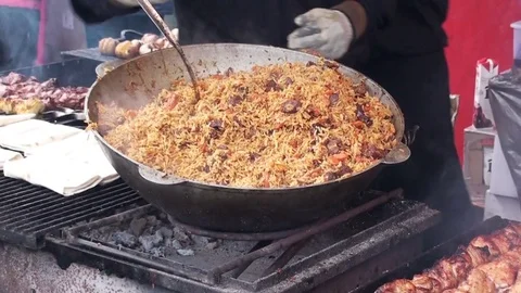 Pilaf is cooked on the grill in a large cauldron Stock Footage 75806848