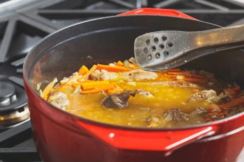 Pilaf cooking process at home in a red dutch oven Stock Photos