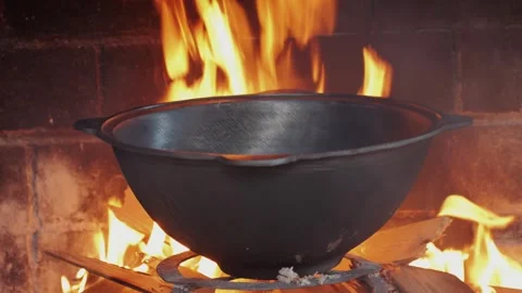Pilaf preparing in a big black cauldron over an open fire. Uzbek plov Stock Footage 257084299