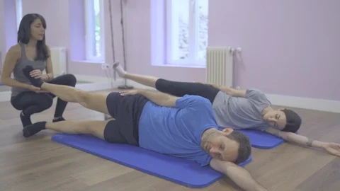 Pilates class with two young students and instructor exercising their bodies. Stock Footage 126983286