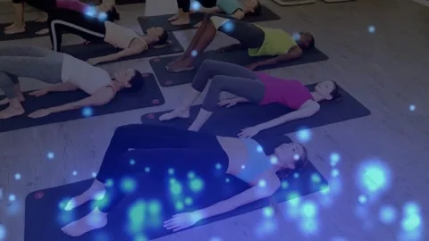 Pilates participants on instructor cue, bridging pelvis on mats, activating core Stock Footage 325964995