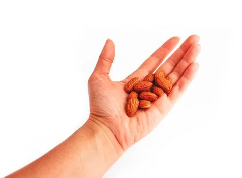 A pile of almond nuts hold in a hand, isolated on white background. Stock Photos