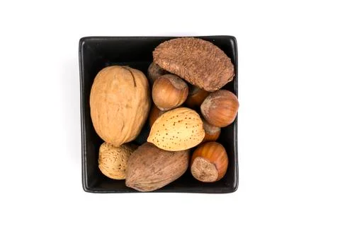 Pile of assorted nuts in the shell in a black bowl isolated over white Stock Photos