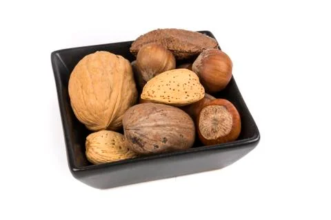 Pile of assorted nuts in the shell in a black bowl isolated over white Stock Photos