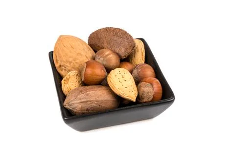 Pile of assorted nuts in the shell in a black bowl isolated over white Stock Photos