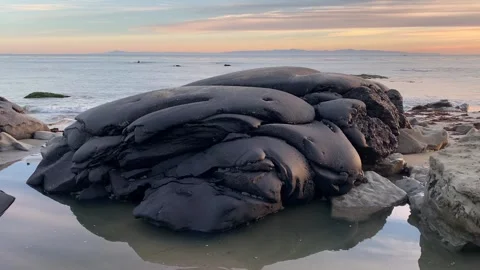 Pile of Black Tar on a Beach at Sunset, Pan Right Video stock 254655251