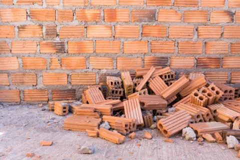 Pile of bricks in construction site with brick wall background 写真素材
