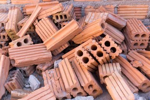Pile of bricks in construction site with brick wall background Stock Photos