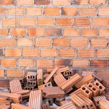 Pile of bricks in construction site with brick wall background Stock Photos