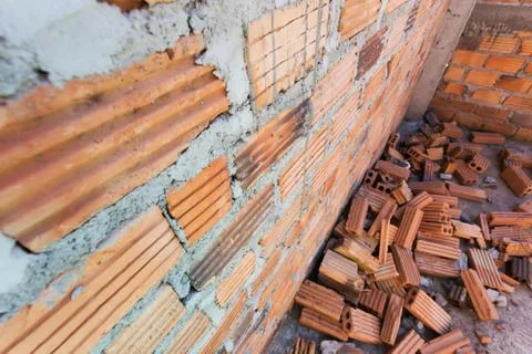 Pile of bricks in construction site with brick wall background Stock Photos