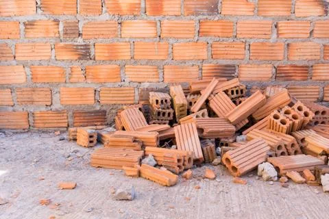Pile of bricks in construction site with brick wall background Stock Photos