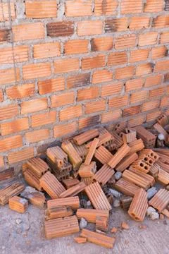 Pile of bricks in construction site with brick wall background Stock Photos