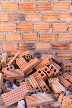Pile of bricks in construction site with brick wall background Stock Photos