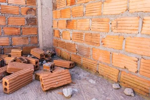Pile of bricks in construction site with brick wall background Stock Photos
