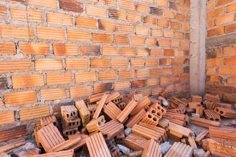 Pile of bricks in construction site with brick wall background Stock Photos