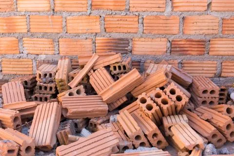 Pile of bricks in construction site with brick wall background Stock Photos