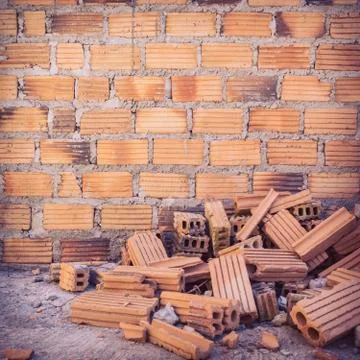 Pile of bricks in construction site with brick wall background 写真素材