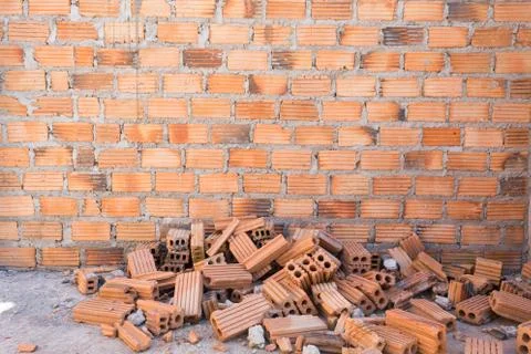 Pile of bricks in construction site with brick wall background Stock Photos