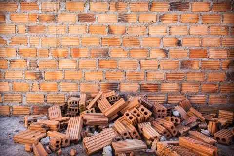Pile of bricks in construction site with brick wall background Stock Photos