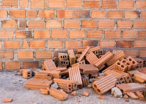 Pile of bricks in construction site with brick wall background Stock Photos