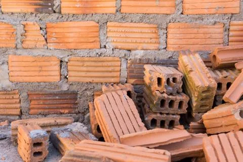 Pile of bricks in construction site with brick wall background Stock Photos