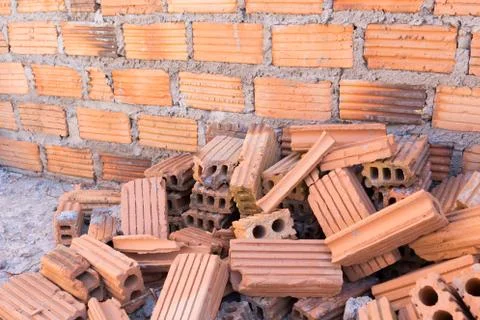 Pile of bricks in construction site with brick wall background Stock Photos