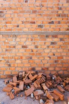Pile of bricks in construction site with brick wall background Stock Photos