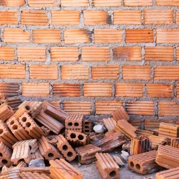 Pile of bricks in construction site with brick wall background Stockfoto's