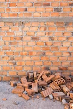 Pile of bricks in construction site with brick wall background Stock Photos