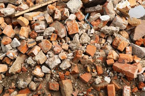 A pile of broken red bricks. Broken bricks close up. Construction debris Stockfoto's