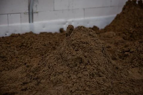 Pile of Brown Soil in Indoor Construction Setting with Exposed Piping 库存照片