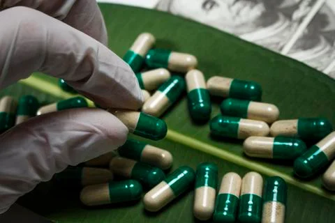 Pile of capsules on green leaf near dollars Stock Photos