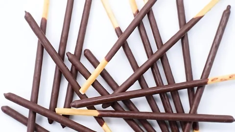 Pile of chocolate covered biscuit sticks, on white plate, close-up, rotating Stock Footage 342188564