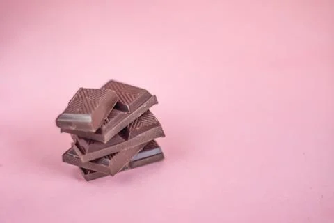 A pile of chocolate on a pink background. Stock Photos