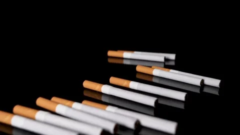Pile of cigarettes are rolled out on a black mirroring surface in slow motion. Stock Footage 146948784