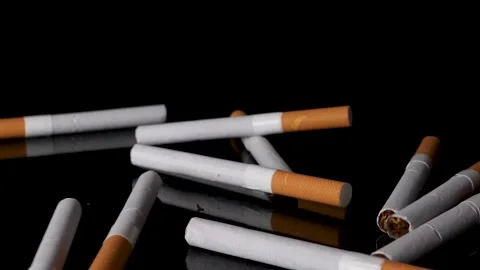Pile of cigarettes dropping and bouncing on black background in slow motion. Stock Footage 146948810
