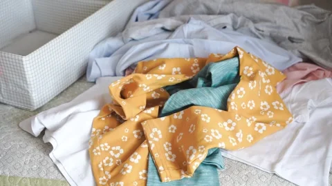 Pile of clean clothes on bed waiting to be organized, household chores Stock Footage 244627161
