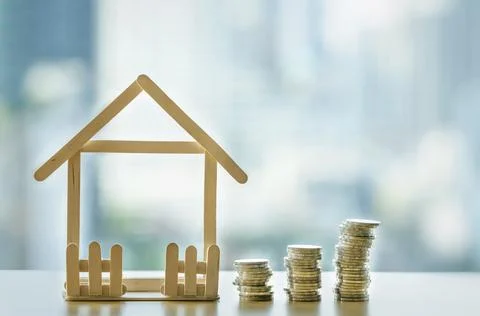 A pile of coins break down. Mini wooden house and row of coin falls. Mortgage Stockfoto's
