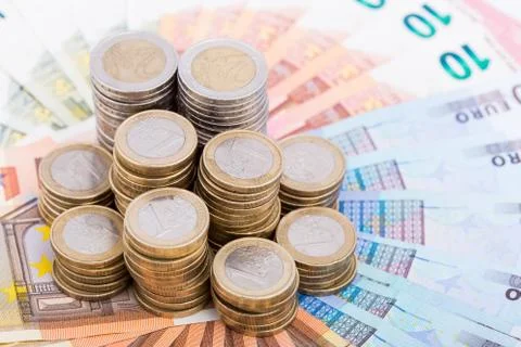 A pile of coins on a fan of bank notes Stock Photos
