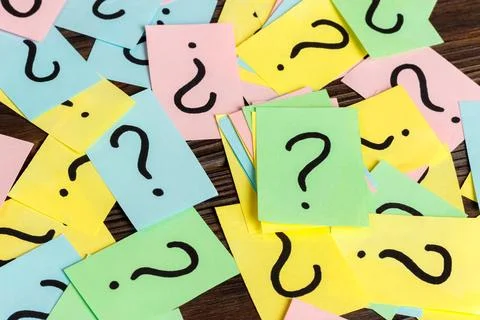 Pile of colorful paper notes with question marks on wooden background. Closeu Stock Photos