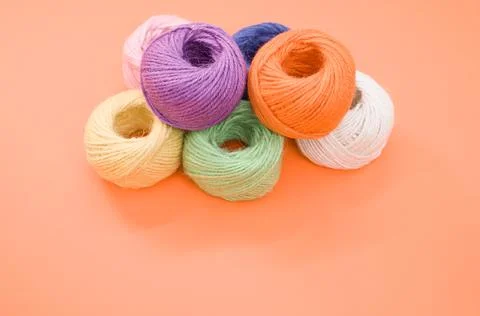 Pile of colorful thread rolls on a orange surface Foto stock