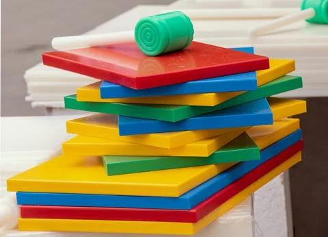 Pile of colour coded colorful plastic chopping boards sold on market stall Stock-Fotos