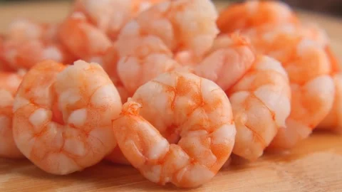 Pile of cooked shrimp with orange shells on wooden cutting board macro view. Stock Footage 332107010