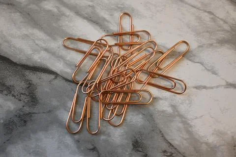 Pile of copper-colored paper clips on a marble surface Fotos de archivo