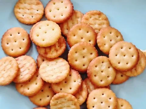 Pile of Crispy Thin Brown Crackers on Light Blue Plate Foto stock