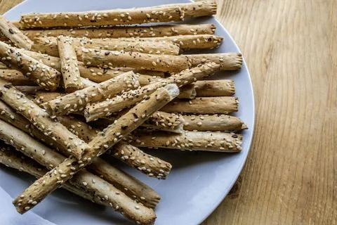 Pile of delicious classic crispy bread sticks (grissini) on a white plate Stock Photos